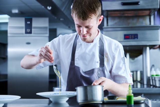 chef cooking in commercial kitchen with Foster fridge cabinet in the background