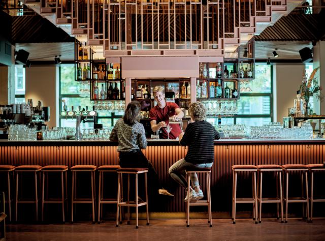 barman serving drinks to two women in a bar