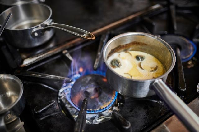 A saucepan can be seen over a gas hob