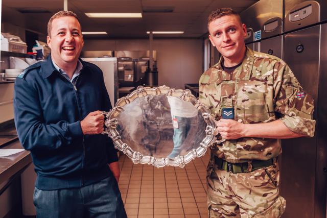 Military men holding a trophy near Foster Refrigerator fridges  