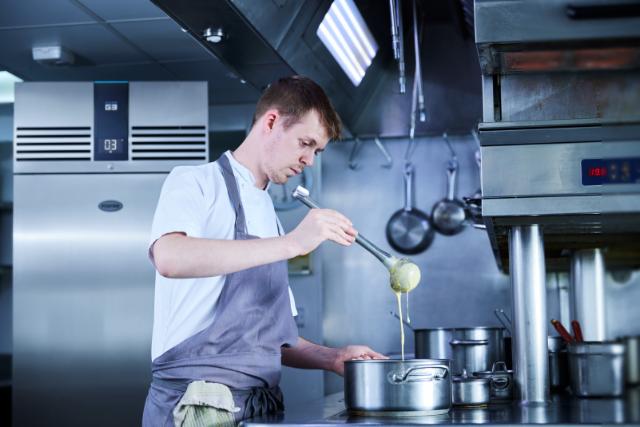 chef cooking in commercial kitchen with Foster cabinet in the background