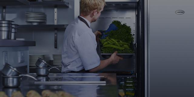 Küchenchef, der Gemüse in einen Foster-Schrank legt
