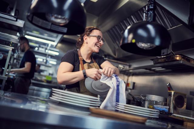 A smiling waitress prepares plates for service