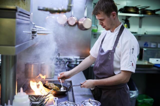 chef cooks over a flaming hob