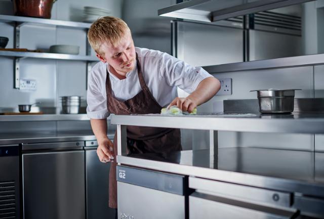 chef cleaning top of Foster counter in kitchen environment 