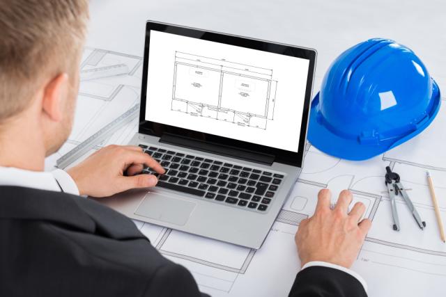 a man works on the layout of a dual compartment coldroom on a laptop