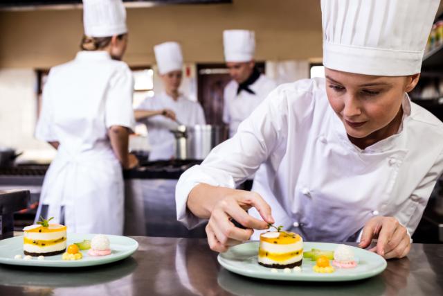 a chef adds the finishing touches to a dish. Other chefs can be seen working in the background