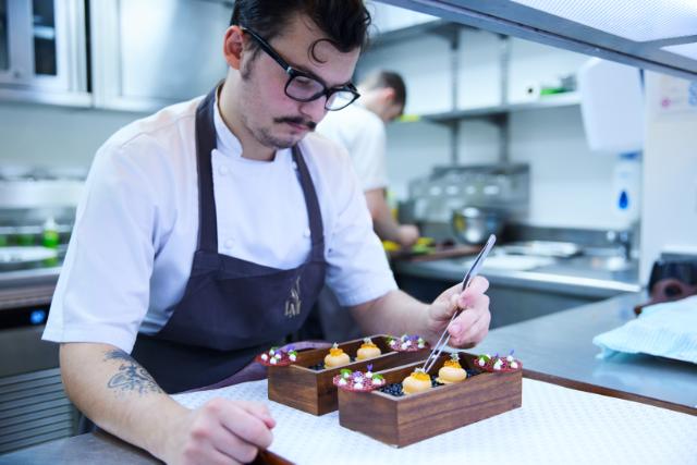 chef adds edible flowers to a dessert