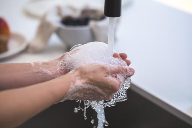 Beeld van handen die onder de kraan worden gewassen